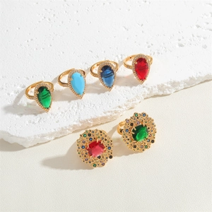 Detailed view of vintage emerald and crystal teardrop rings on white marble stone