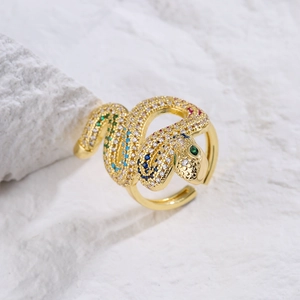 Gold-plated snake-shaped open ring with multicolor zircon stones on stone background