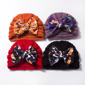 Detail of four baby knit hats with Halloween pumpkin, spider, and ghost bow patterns