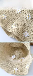Close-up of paper straw sun hat with woven texture, daisy applique and interior sweatband