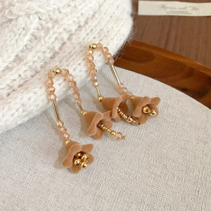 Dettaglio ravvicinato di orecchini a fiori vintage con perle champagne e nappe