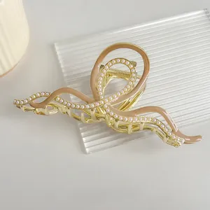 Detailed macro view of a golden wave hair claw clip with pearls and enamel inlay