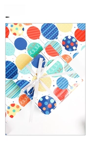 Gift box wrapped in colorful balloon pattern paper with a white silk ribbon detail