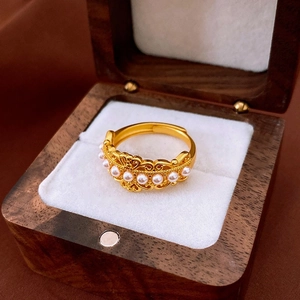 Détail macro d'une bague vintage dorée avec motifs floraux ajourés et perles chic