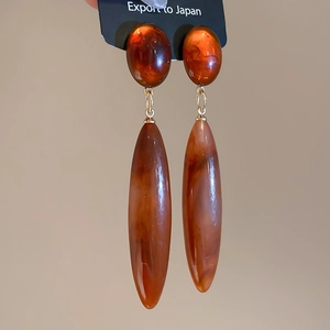 Macro shot of tortoiseshell acrylic drop earrings with polished marble texture finish