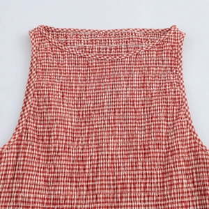 Detail of red and white gingham smocked bodice with elastic texture and neckline