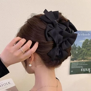 Elegant large black satin bow hair claw clip for women shown on a model hairstyle