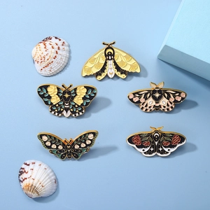 Close-up of cute cartoon enamel moth and butterfly pins on a blue decorative background