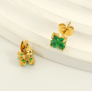 Détail de boucles d'oreilles trèfle avec gemmes vertes en cœur et finition en or acier
