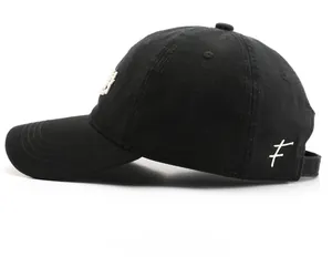 Side view of black cotton twill baseball cap showing white embroidery and fabric texture