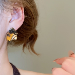 Close-up of 18k gold-plated geometric earring with amber resin texture on model