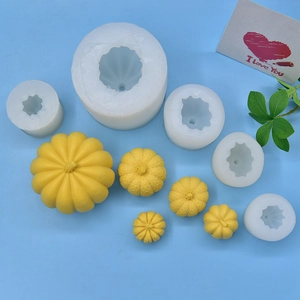 Detailed view of pumpkin silicone molds and yellow candles in various sizes on blue background