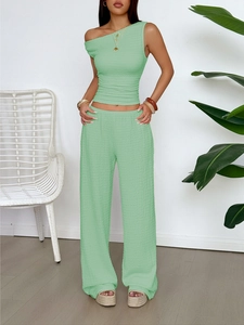 Detail of green sleeveless top and wide leg trousers set with textured fabric finish