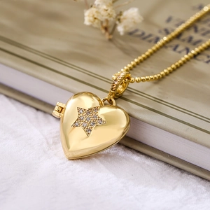 Gold heart locket necklace with star zircon on a vintage book with dried flowers