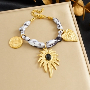 Detail of silk scarf bracelet featuring gold pendants and heart charms on display