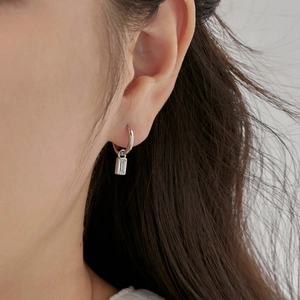Detailed view of silver hoop earrings featuring a clear rectangular zircon pendant on a model