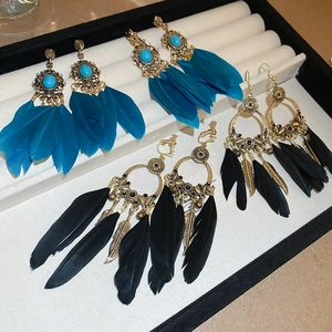 Détail de quatre paires de boucles d'oreilles bohèmes avec plumes et pierres bleues sur plateau