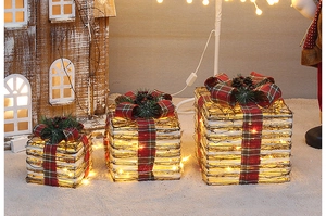 Close-up of lighted natural rattan Christmas gift box set with festive pine and bows