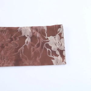 Detailed macro shot showing the brown floral embroidery and sheer fabric texture on the cuff