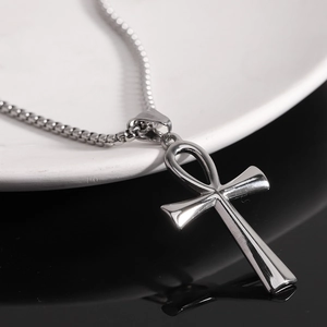 Polished silver stainless steel Ankh cross necklace with box chain on a dark reflective surface