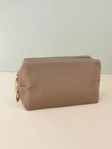 Detailed close-up of brown cross-grain PU leather texture and gold metal zipper on cosmetic bag