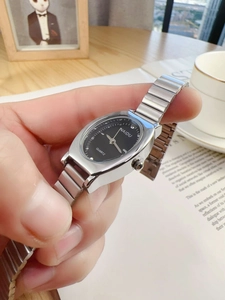 Detail of elegant silver quartz watch with black oval dial and metal elastic band