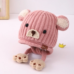 Detail der rosa Strickmütze mit Bärenohren, Knopfaugen und weichen Pfoten-Ohrklappen