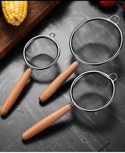 Three stainless steel fine mesh strainers with wooden handles in various sizes on a table