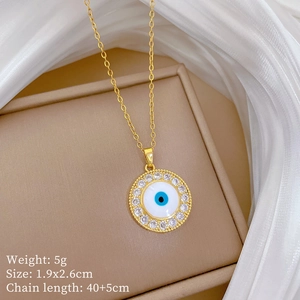 Detail view of a gold evil eye pendant necklace with crystals on a beige jewelry box