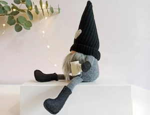 Détail d'un gnome de Noël en tricot avec de longues jambes tenant une tasse à café