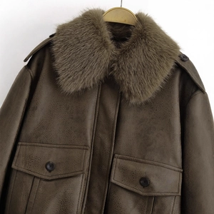 Dark brown leather cargo jacket with a detachable faux fur collar on wooden hanger