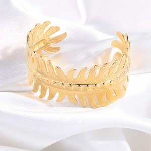 Detailed macro view of the golden leaf pattern and central bead texture on the wide cuff bracelet