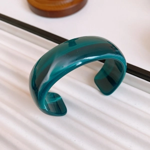 Detail view of vintage gold-plated mother of pearl open bangle with green resin marble texture