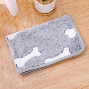 Detail view of grey pet blanket with white bone patterns on wooden floor background
