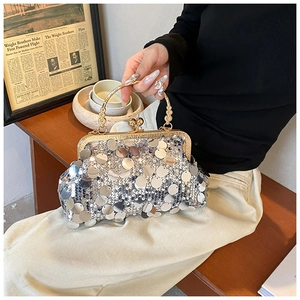Close-up of a silver sequin evening bag with a golden metal handle on a vintage table