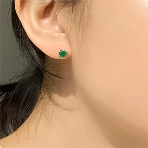 Detail shot of heart-shaped green zircon stud earring worn on a model's ear