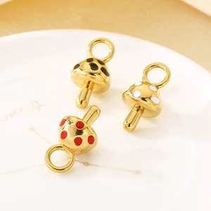 Macro shot of three colorful enamel mushroom pendants with golden rings on a ceramic plate