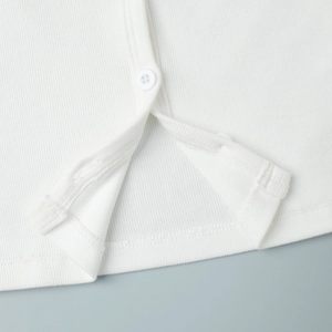 Detail of white ribbed knit cardigan featuring matching buttons and refined hem stitching