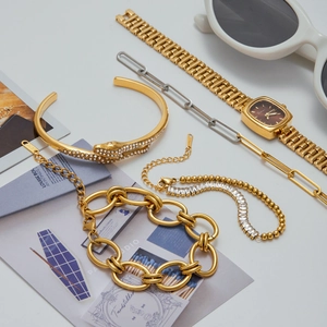 Ensemble bracelet serpent doré avec montre en strass et lunettes sur fond élégant