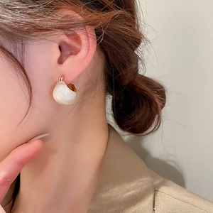 Model wearing elegant gold-plated C-shaped earrings with white enamel finish