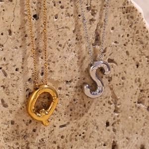 Macro-opname van 3D ballon letterhangers in goud en zilver op een beige stenen ondergrond