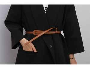 Detail of a slim brown leather belt tied in a bow over a stylish black blazer