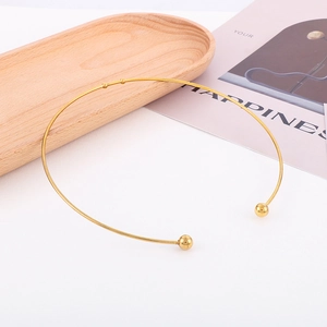 Collier ras du cou doré en acier inoxydable en forme de C sur un plateau en bois