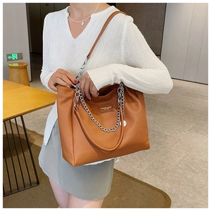 Detail of vintage brown leather tote bag with silver chain and embossed fashion logo