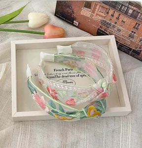 Detailed embroidery of colorful flowers and green leaves on white mesh headbands
