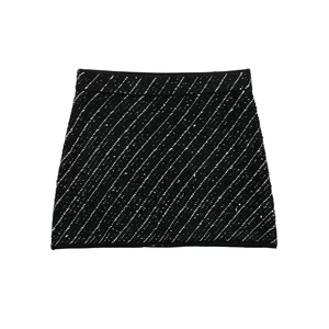Detailed flat lay of black knit mini skirt with white diagonal texture and tweed finish