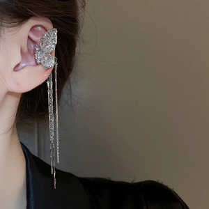 Close-up of silver butterfly ear cuff with sparkling zircons and long metal tassels