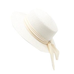 Detail of white straw sun hat with wide brim and elegant beige ribbon bow decoration