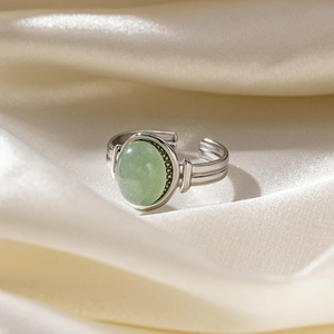 Macro detail of vintage adjustable ring with oval green stone on white silk