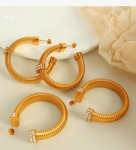 Detailed view of gold C-shape twisted earrings featuring sparkling rhinestone inlay